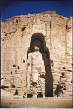 Close-up of Buddha of Bamiyan; bottom right, an Afghan standing on a foot of the statue 